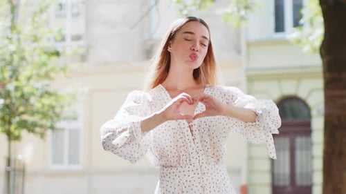 Smiling Woman Making Heart Shape in City