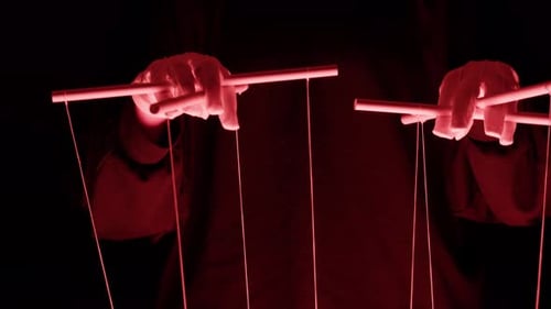 The Puppeteer Controls the Puppets in the Theater in Red Neon Light Closeup Managing People at Work