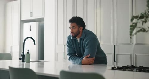 Man Leans on Island Countertop in Modern Kitchen