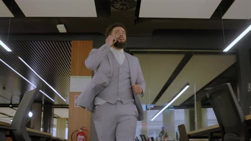 Businessman Walking and Talking on Phone in Office