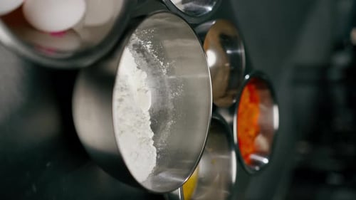 Vídeo vertical de primer plano en una cocina profesional: hay cuencos de hierro con ingredientes en una plancha