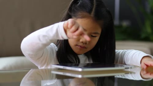 Girl Interacting With Tablet Device on Table Indoors