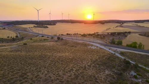 Silhouetten, Windmühlen, große orangefarbene Sonnenscheibe, Sommerlinsenlicht und Hochgeschwindigkeitsbahninfrastruktur