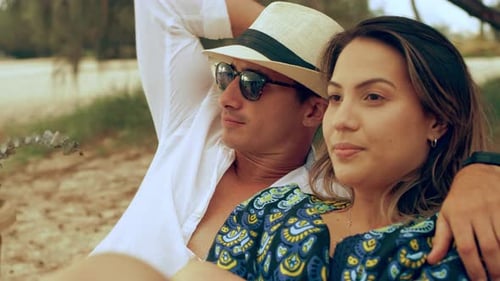 Young Couple Sitting and Looking Out at the Ocean on the Beach