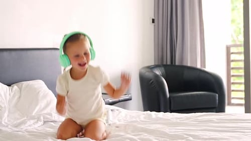 Happy Girl Dancing on Bed with Headphones