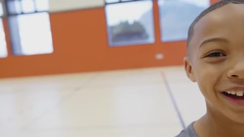Smiling boy in school gymnasium enjoying physical education class activities