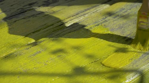 Yellow paint applied to wooden planks with brush