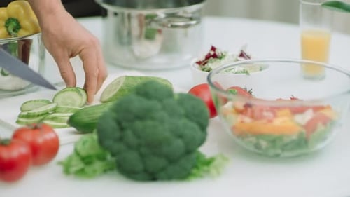 Hands Cutting Cucumber in Bright Kitchen for Salad