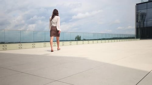 Businesswoman Walks on Rooftop Patio During Day