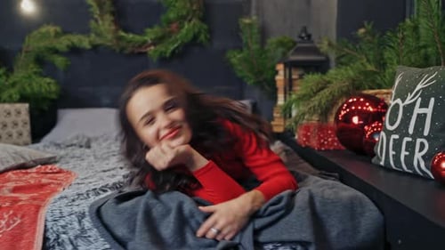 Smiling Woman Lying on Bed Near Christmas Decorations