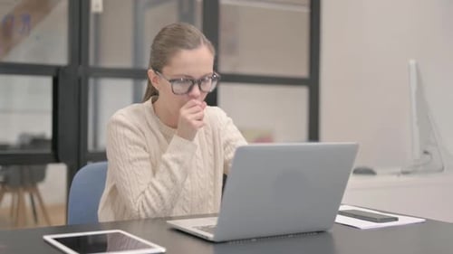 Coughing Young Woman Using Laptop in Office