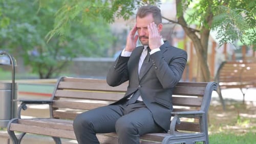 Middle Aged Businessman with Migraine Sitting Outdoor