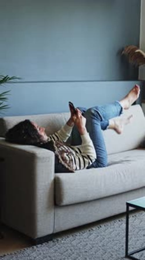 Woman Relaxing on Couch Looking at Smartphone
