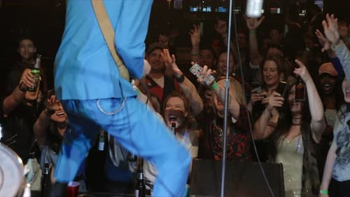 Enthusiastic Male Rock Musician Playing Guitar and Signing on Stage for Dancing
