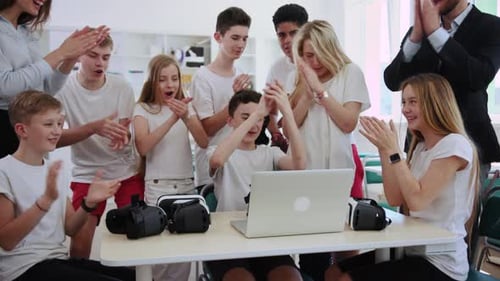 Enthusiastic Students Clapping in Classroom Watching Laptop