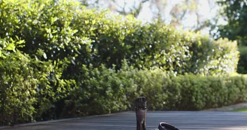 Water bottle, headphones, towel and yoga mat on deck in sunny garden, copy space, slow motion