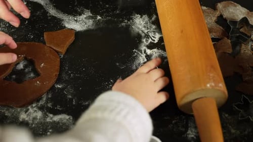 Mother rolling gingerbread dough beside wooden pin star cookie cutter nearby preparing festive sweet