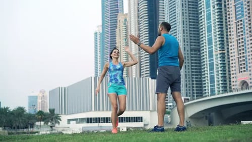 Young Woman Running in Park and Her Personal Trainer Checking Time On