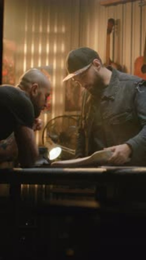 Men Examining Sculpture in Dimly Lit Workshop