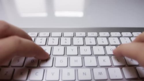 Nahaufnahme von Finger, die etwas auf einer weißen Tastatur tippen