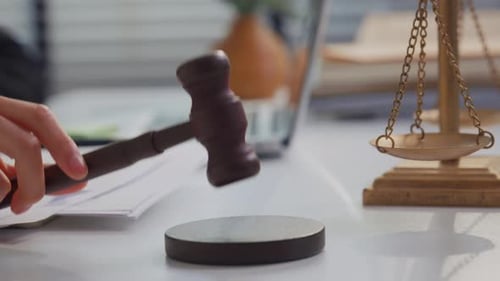 Primer plano de la mano de una abogada golpeando a la justicia en la sala del tribunal.