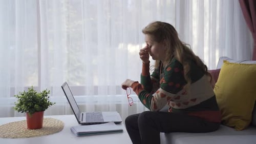 Tired Woman Working on Laptop at Home