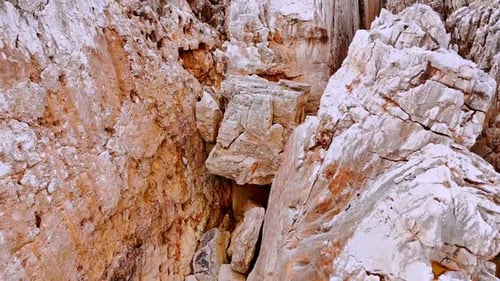 Light brown rocks with no vegetation on. Unapproachable bare mountains with cracks in. Aerial view.