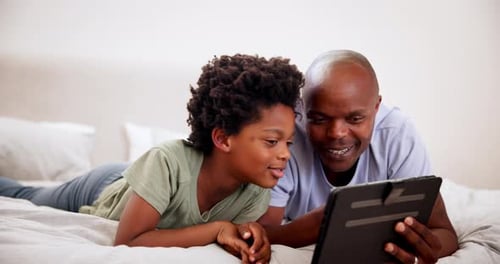 Boy and Adult Enjoying Tablet Together on Bed