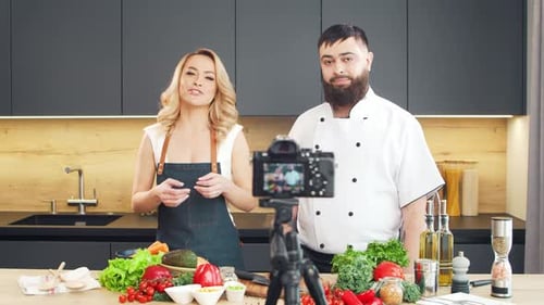Junge Frau und Mann bereiten Essen zu und veranstalten eine Kochshow, die Blogger aus Kitchen Healthy streamen