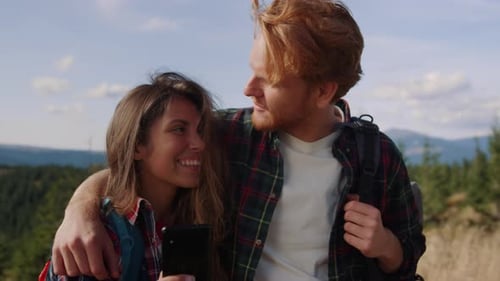 Happy Couple with Mobile Phone Standing on Top of Mountain. Loving Man