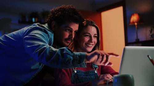 Couple Smiling Together at Laptop Computer at Night