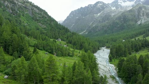 Drone flight over a winding glacier river through a high mountain alpine valley.