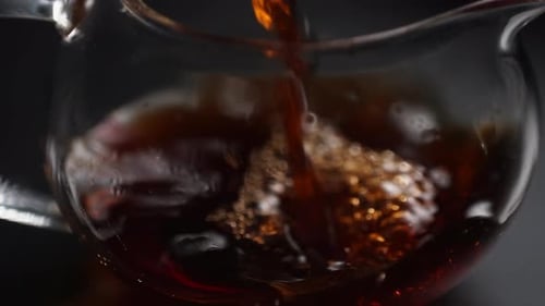 Dark Liquid Being Poured Into Glass Container