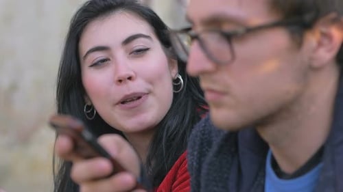 man focused on his smartphone while girlfriend talking to him