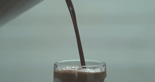 Hot Chocolate Poured In A Tall Ice Cream Glass On A Marble Countertop. Medium Shot With Shallow D...