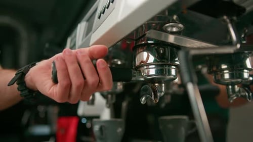 Pouring coffee flows from the machine into the cup making hot drink using the filter holder freshly