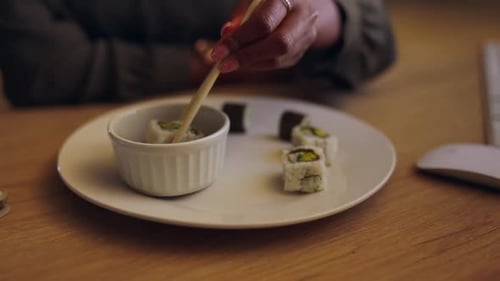 Sushi, chopsticks and a business person eating in an office while working late at night