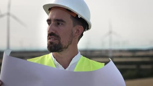 Male Engineer Worker with Safety Helmet Inspecting Blueprint Map Working in Wind Turbine Power