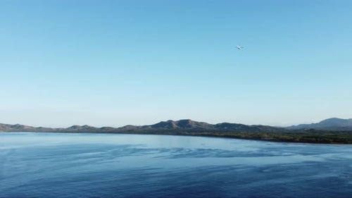 A plane flying over the Pacific Ocean just off the coast line of Playa Tamarindo, a young, fun, and