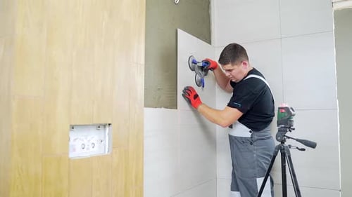 Male worker professional master laying ceramic tiles on the wall in the bathroom. Portrait