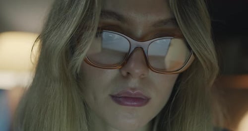 Closeup of Female Face Wearing Trendy Eyeglasses Concentrated on Office Work at Night