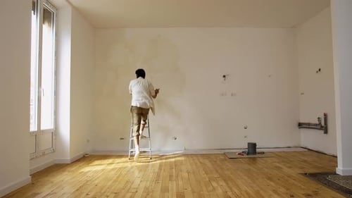 Man Repairing Wall in Empty Apartment