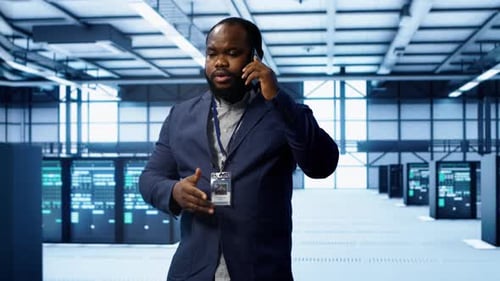 IT Technician Talking on Phone in Data Center Coordinating Server Maintenance