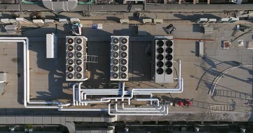 Industrial building rooftops with vents and pipes lined across, Top down view