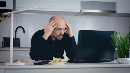 Stressed Man Working on Laptop at Home