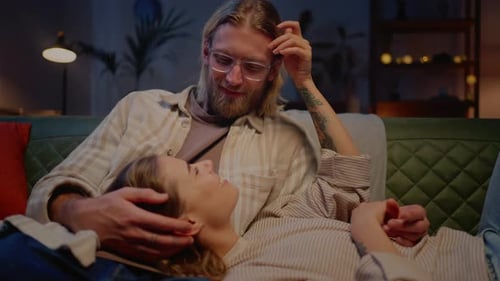 Woman Lying on Husband Knees While Relaxing on Couch Indoors