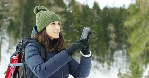 Woman Using Mobile Phone on Snowy Winter Hike