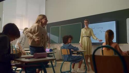 Estudiantes mestizos que aprenden en la escuela primaria. Profesora de pie en Blackboard