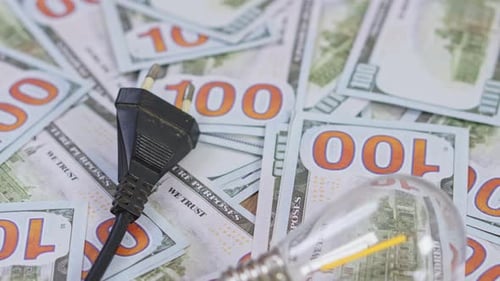 Energy saving concept with light bulb and power plug on dollar bills