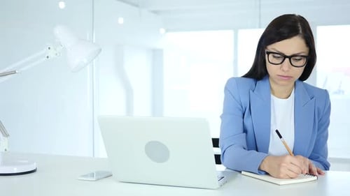 Young Businesswoman Writing in Office Documentation